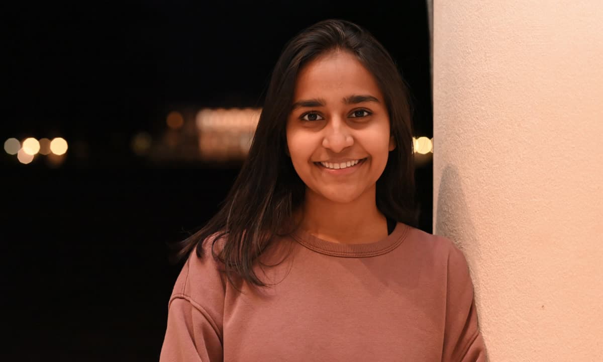 Sarrah Abdulali smiling in a brown sweater